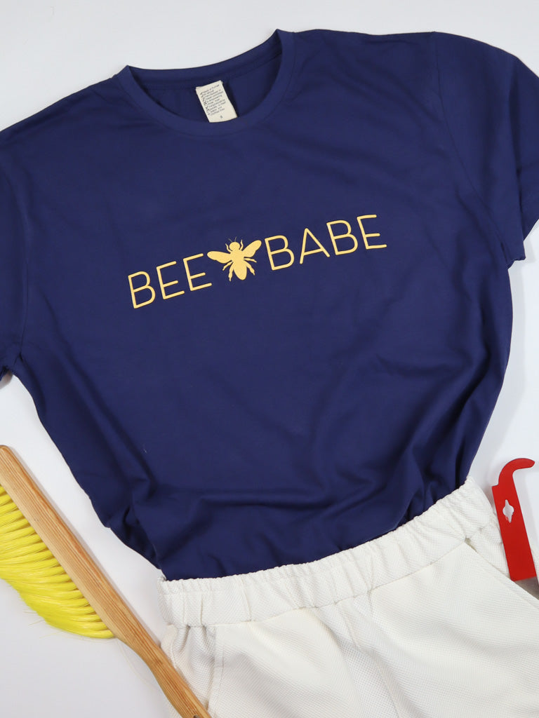 Navy blue tee shirt with the phrase "bee babe" written across the front in gold lettering.