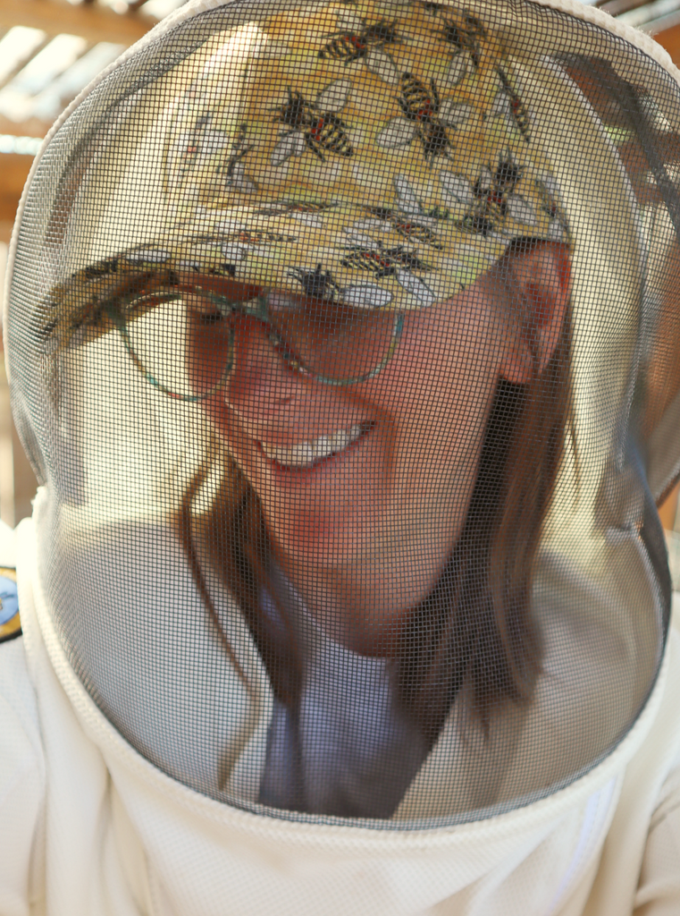 Woman wearing Baseball hat with yellow honeycomb background and large honeybees.