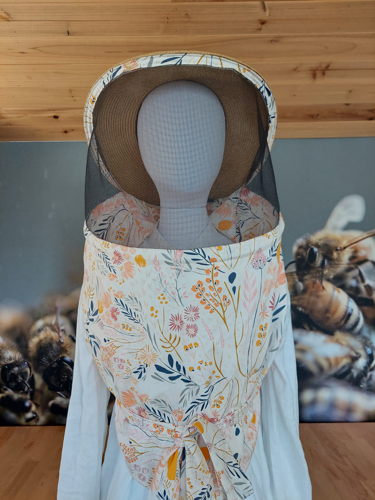 Women's beekeeper veil with floral print fabric and brown hat.