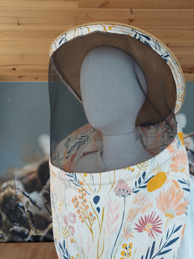 Women's beekeeper veil with floral print fabric and brown hat.